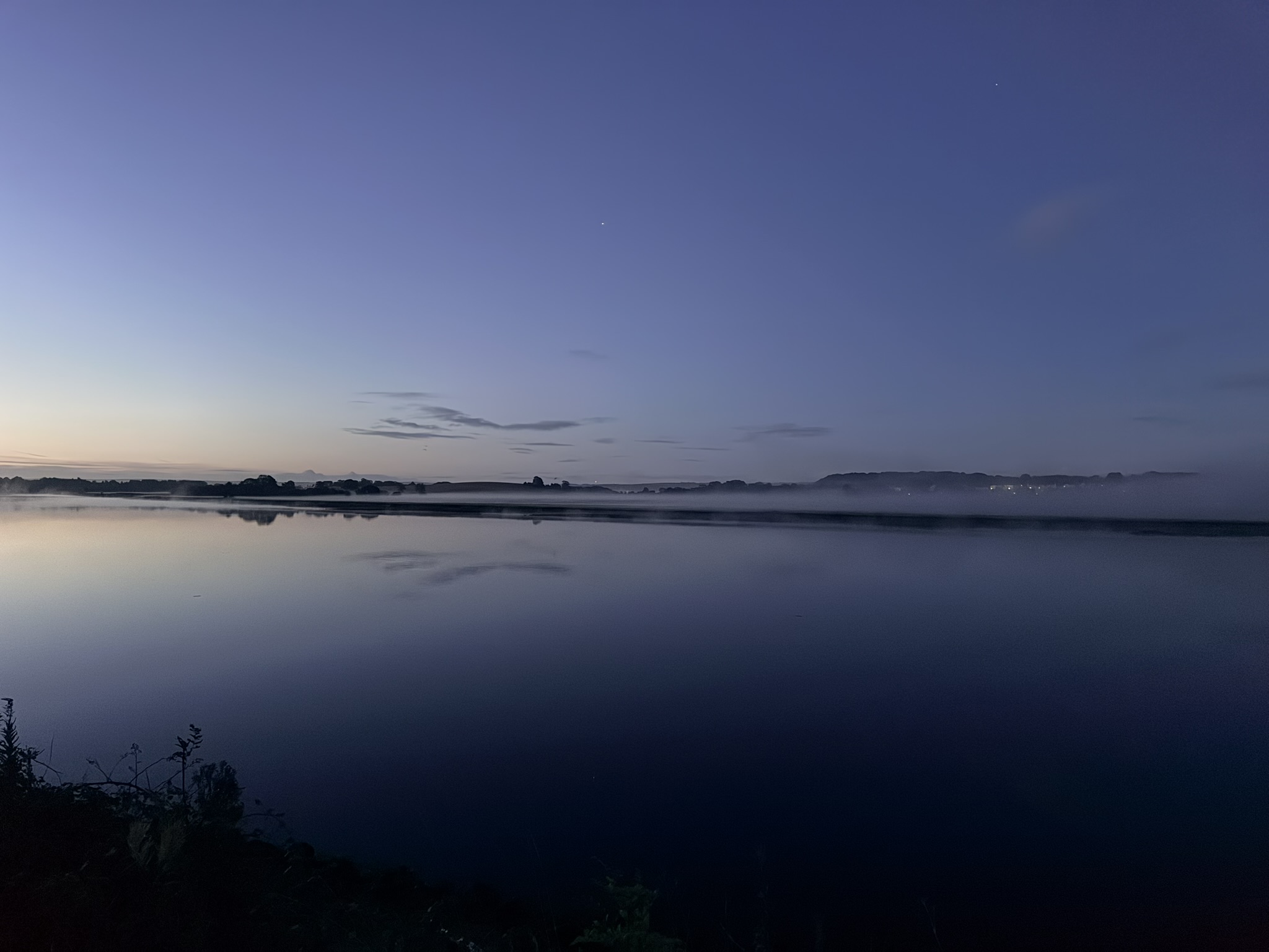 A flat band of mist on the Clyde, with lights showing through and a clear sky above